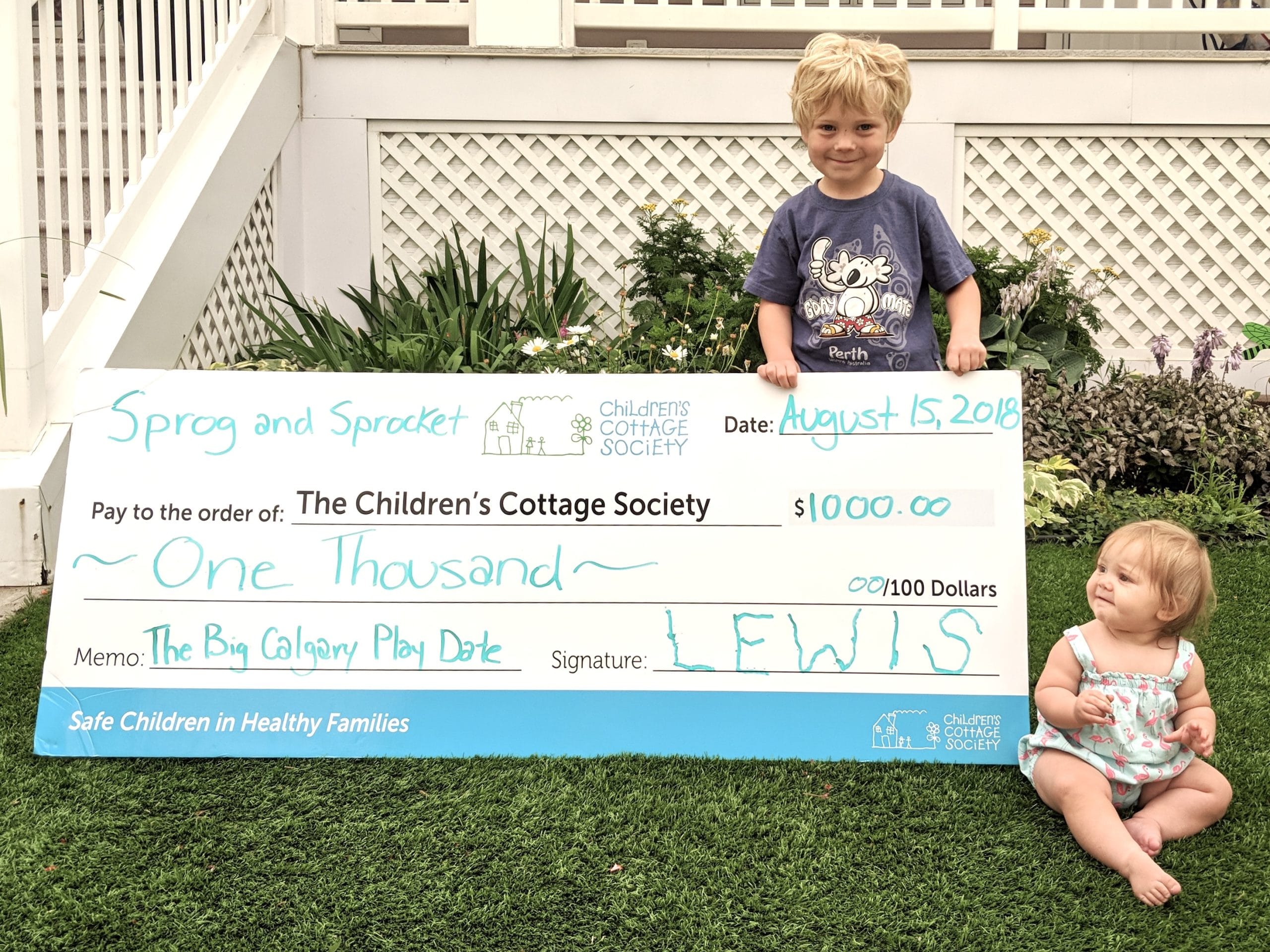 A boy and girl with a big check for The Children's Cottage Society.