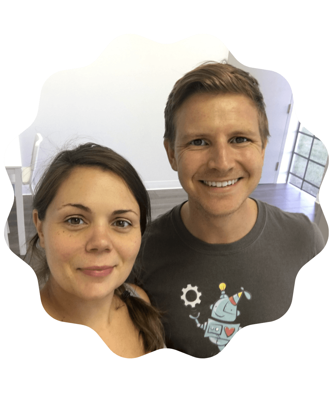 A man and woman smiling at the camera inside a brightly lit room.