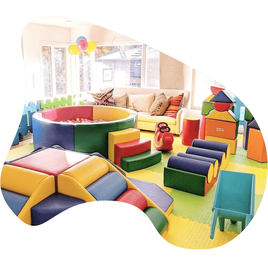 Brightly colored playroom with soft play blocks and a ball pit.