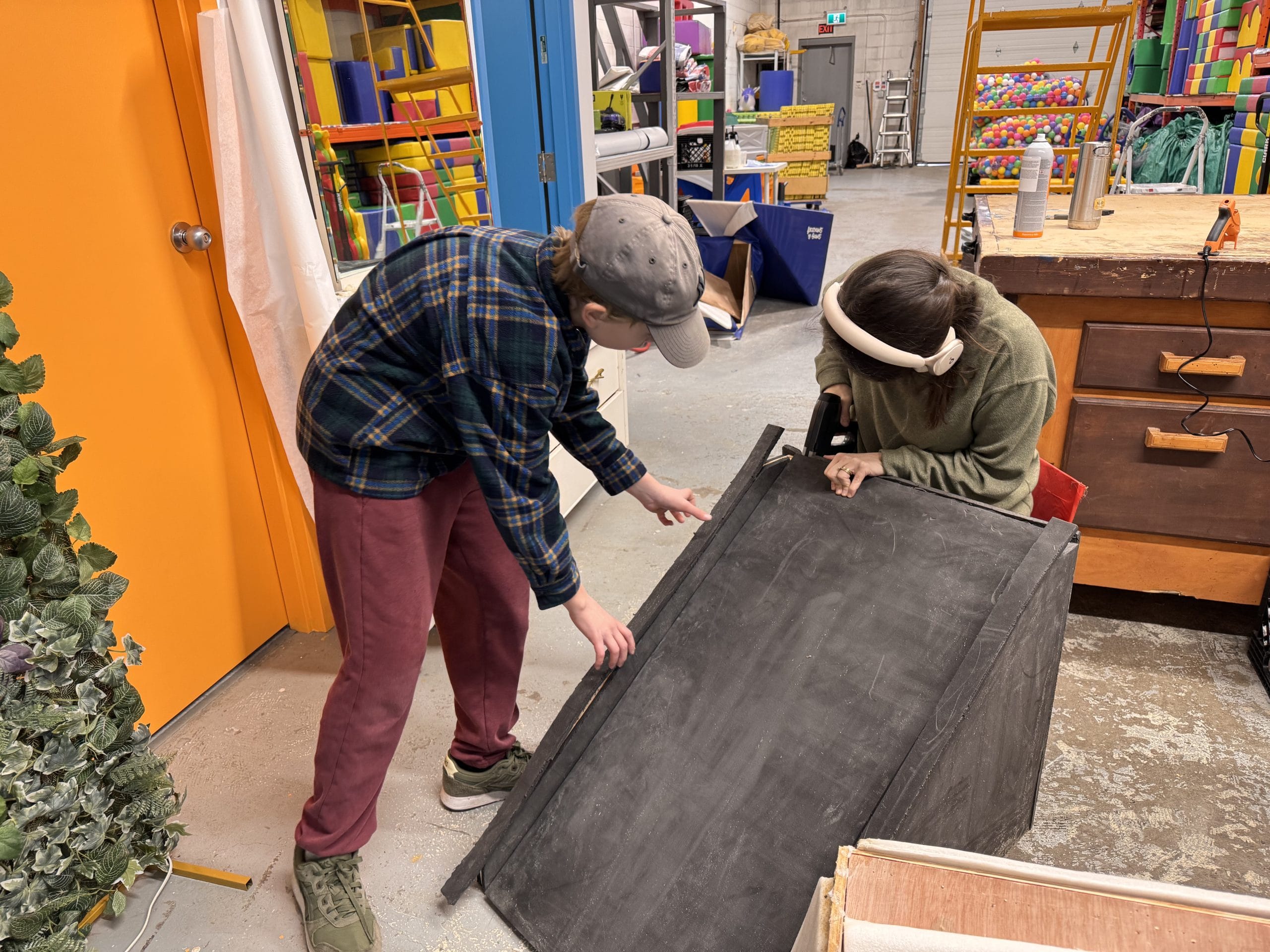 Two individuals working together on a blackboard in a workshop environment.